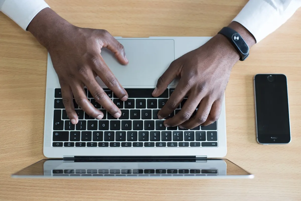 Hands typing at a laptop — illustrative photograph of sustained desk posture